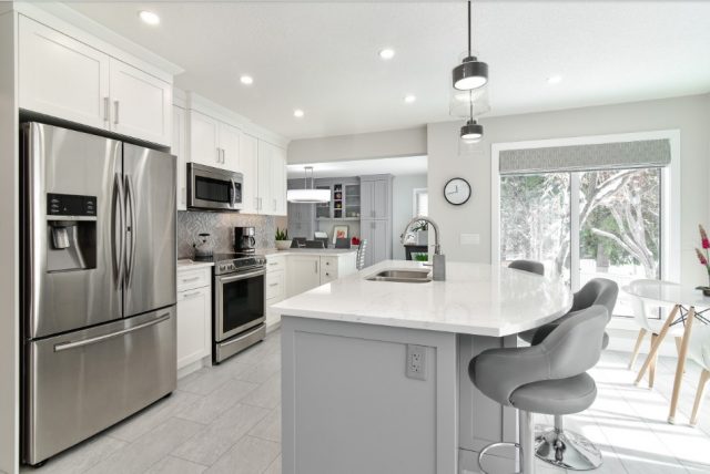 Two toned kitchen with grey island and white cupboards from a home renovation